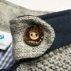 Gros plan d'un bouton en bois sur manteau tricoté
